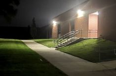 a building with stairs and lights on at night in front of the grass lawn area