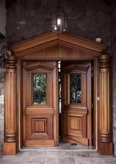 two wooden doors are open in front of a stone wall