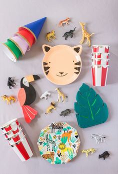 various toy animals and other toys on a table with paper plates, cups, and napkins