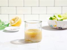 a glass jar filled with liquid sitting on top of a table next to a bowl of salad