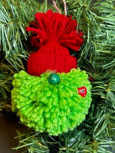 an ornament hanging from a christmas tree with green and red yarn on it