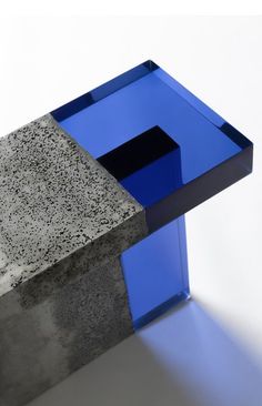 a blue object sitting on top of a cement block next to a white wall and floor