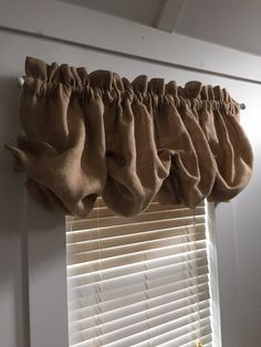 the curtain is hanging on the side of the window in front of the blinds,