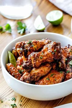 a white bowl filled with chicken wings covered in sauce and garnished with cilantro