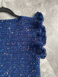 a blue knitted cloth with sprinkles and a black wooden hanger