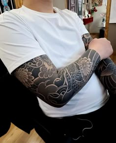 a man with tattoos on his arm sitting in a chair