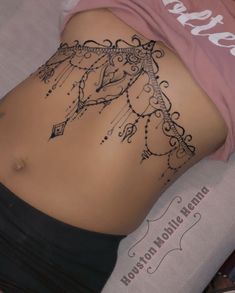 a woman laying on top of a bed with her stomach covered in hendi tattoos