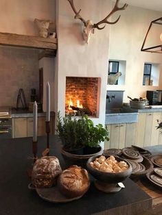 a table with breads and vegetables on it in front of a fire place that is built into the wall