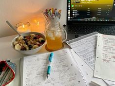 a laptop computer sitting on top of a desk next to a bowl of fruit and cereal