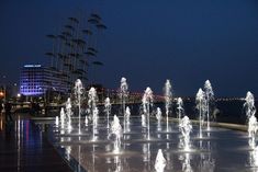 the fountains are lit up at night by the water