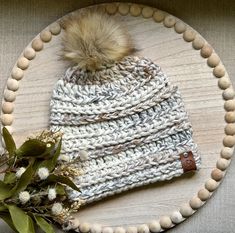 a white hat with a brown pom - pom on it sitting on top of a wooden plate