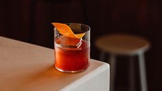 an orange peel garnishes the top of a cocktail