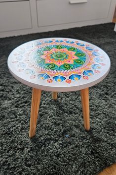 a white table with colorful designs on it in the middle of a carpeted room