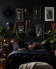 a bedroom with black walls and pictures on the wall, candles in front of the bed