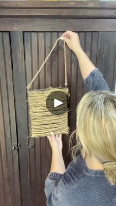 a woman is holding a string hanging from a wooden door with a video on it