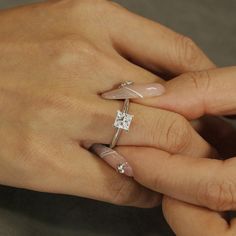 a woman's hand with two rings on her fingers and a diamond ring in the middle