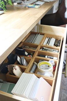 an open drawer with lots of crafting supplies in it and some books on the table