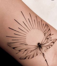 a black and white photo of a sun tattoo on the side of a woman's thigh