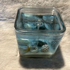 a glass container filled with sea shells and sand