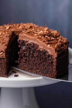 a chocolate cake with one slice cut out on a white plate and the other half eaten