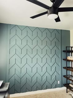 a ceiling fan is hanging in front of a blue wall with geometric designs on it