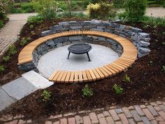 a wooden bench sitting in the middle of a stone circular fire pit surrounded by brick walkways