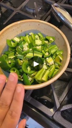 someone is cooking green peppers in a bowl on top of the gas stove, and then flipping them over