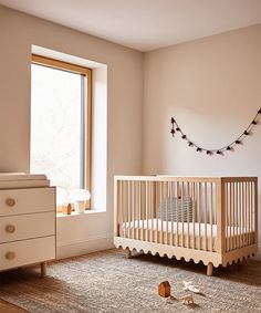 a baby's room with a crib, dresser and window