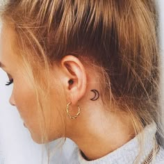 a woman with a small crescent tattoo on her left side of her neck and behind her ear