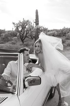 the bride and groom are getting out of their convertible car to ride in the desert