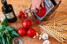 a person is grating tomatoes on top of pasta and other ingredients to make an appetizer