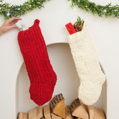 two stockings hanging from the side of a fireplace with wood stacked in front of them