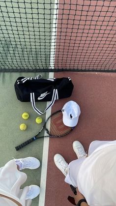 two tennis players standing next to each other with their rackets and balls on the ground