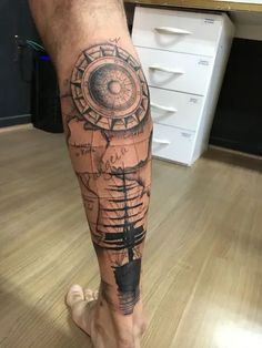 a man's leg with a compass tattoo on it