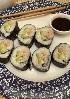 sushi on a plate with chopsticks next to it and a cup of coffee