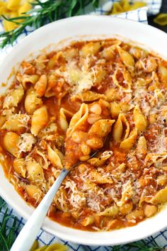 a white bowl filled with pasta and sauce on top of a blue and white table cloth