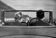 two people sitting in an old car looking out the window