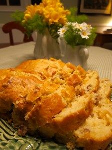 a loaf of bread sitting on top of a green plate next to a vase with yellow flowers