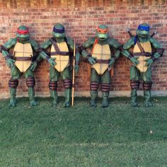 four teenage mutant turtles standing in front of a brick wall with their backs to the camera