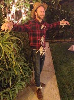 a man wearing a cowboy hat standing next to a bush with lights on it's sides