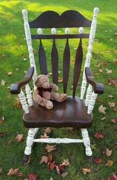 a teddy bear sitting in a wooden rocking chair on the grass with leaves around it