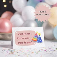 a card with a birthday hat on it sitting in front of balloons and confetti