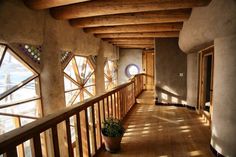 a long hallway with wooden railings and potted plants on the side, in front of large windows