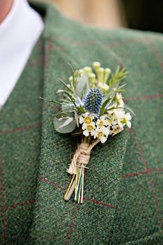 a boutonniere with flowers and greenery on the lapel of a man