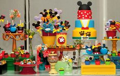 a table topped with lots of cakes and cupcakes covered in mickey mouse decorations