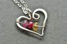 two hearts in a heart shaped pendant on a silver chain, with one red and one yellow bead