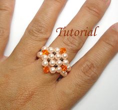 a woman's hand with an orange and white beaded ring on top of it