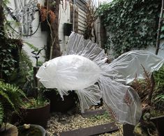 a white fish statue sitting in the middle of a garden