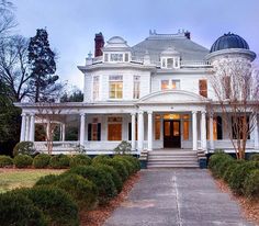 a large white house sitting in the middle of a lush green field