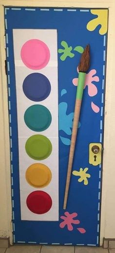 a painting brush sitting on top of a door with paint swaters and circles painted on it